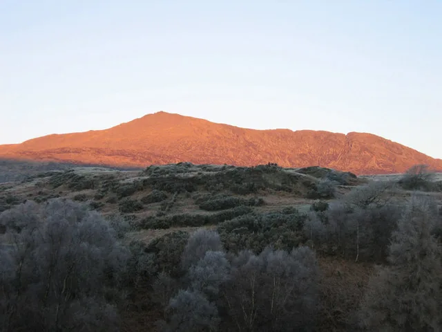 The slate crag and summit of Moel Siabod rising above forest and moorland near Capel Curig, Conwy.