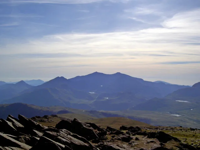 Layered blue ridges falling away toward the Snowdon massif on the skyline, seen over broken rock from the top of Moel Siabod