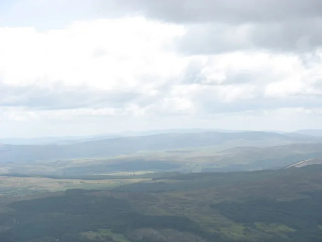 A green, forested panorama over Eryri's lower slopes, seen from the summit of Moel Siabod