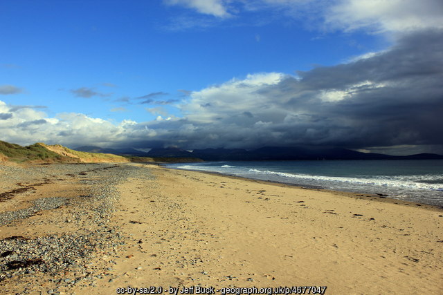 The mountains of Eryri (Snowdonia) seen across the Menai Strait from Newborough Beach on a clear day.