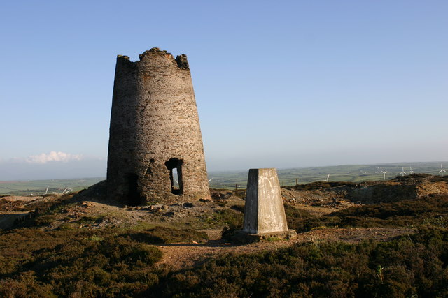 The ruined windmill tower on the Parys Mountain ridge, its stone structure silhouetted against the open Anglesey sky.