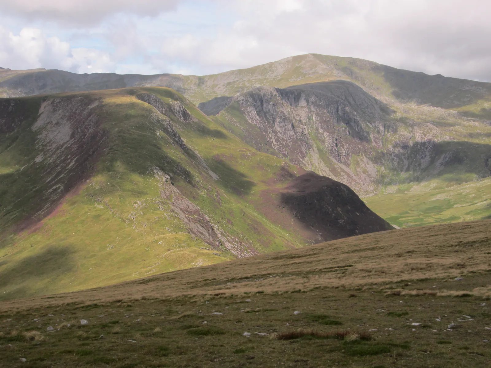 The Carneddau ridges seen from the descent off Pen Llithrig y Wrach, steep grass falling away in the foreground