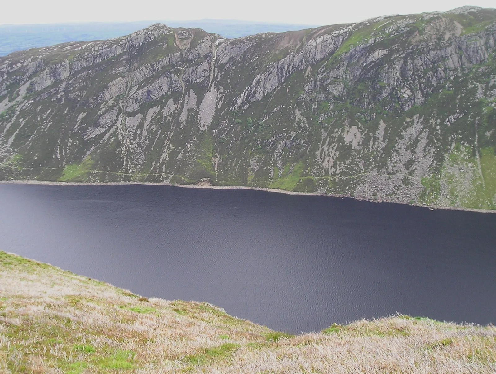 Llyn Cowlyd lying dark beneath the broken crag face of Creigiau Gleision