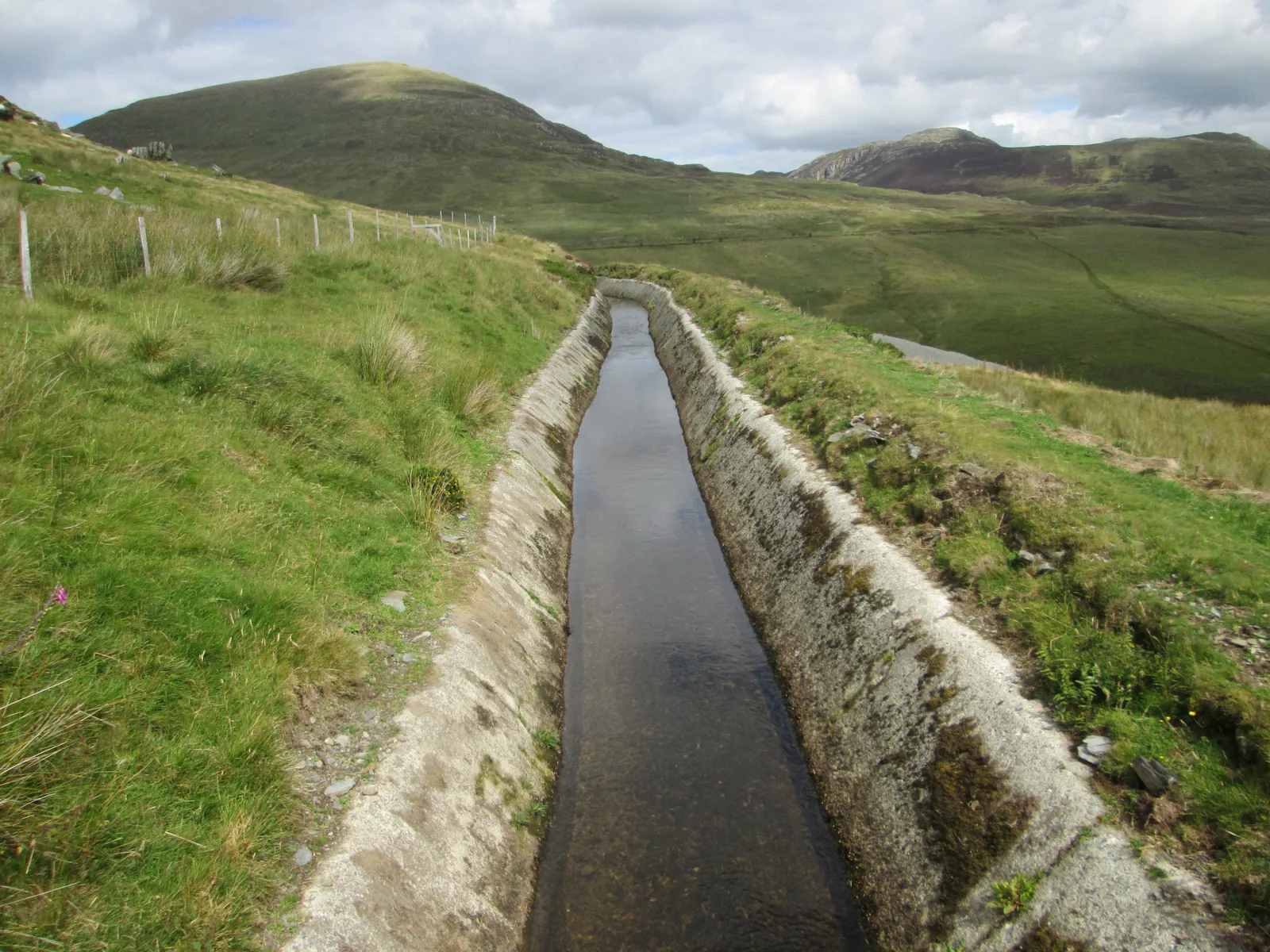 The stone-lined water leat on Pen yr Helgi Du, running toward the grassy dome of Pen Llithrig y Wrach