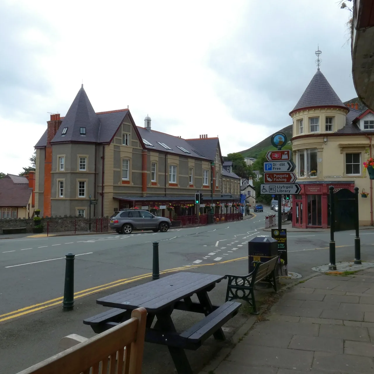 The centre of Penmaenmawr, a Victorian corner building with a turret above the junction and benches on the pavement