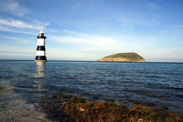 The black-and-white Trwyn Du Lighthouse on its rock off Penmon Point, with Puffin Island lying low across the sound.