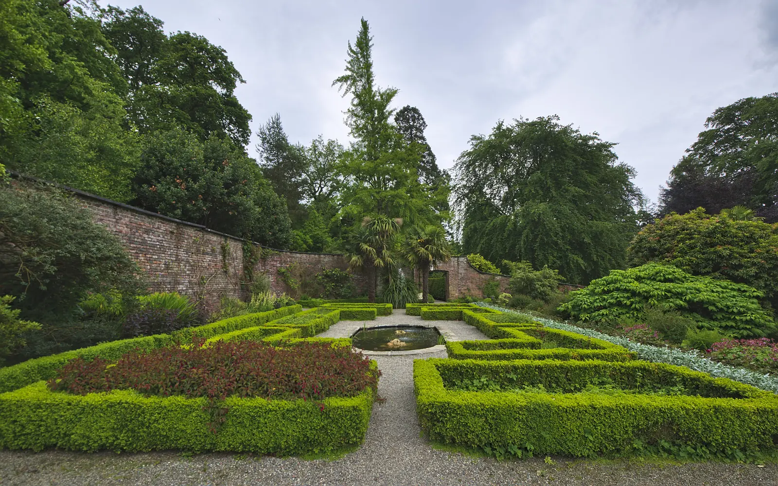 The formal Walled Garden at Penrhyn Castle, with clipped box hedging and a central pond inside a brick wall.