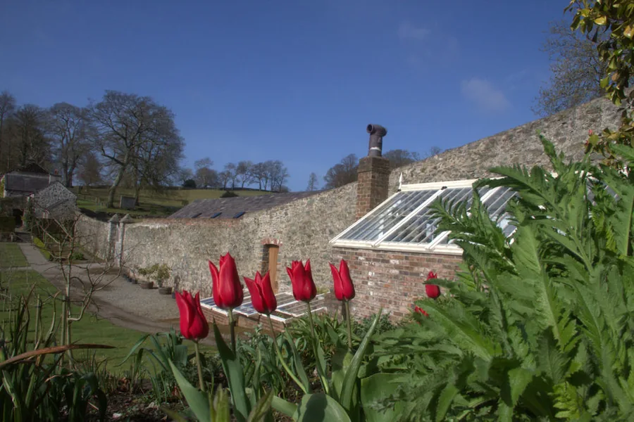 Spring colour in the restored gardens at Plas Cadnant, borders in bloom by the curving walled garden near Menai Bridge, Anglesey.