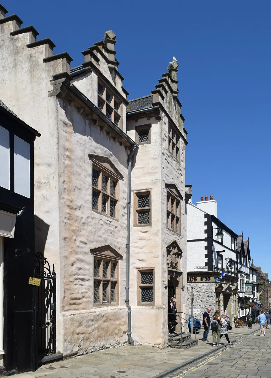 The whitewashed, stepped-gable front of Plas Mawr, an Elizabethan town house on a cobbled Conwy street.
