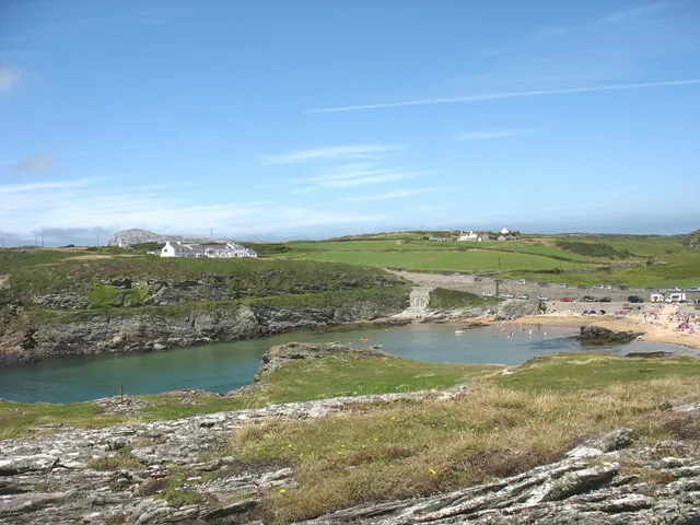 Porth Dafarch cove seen from the south, turquoise water framed by low rocky headlands.