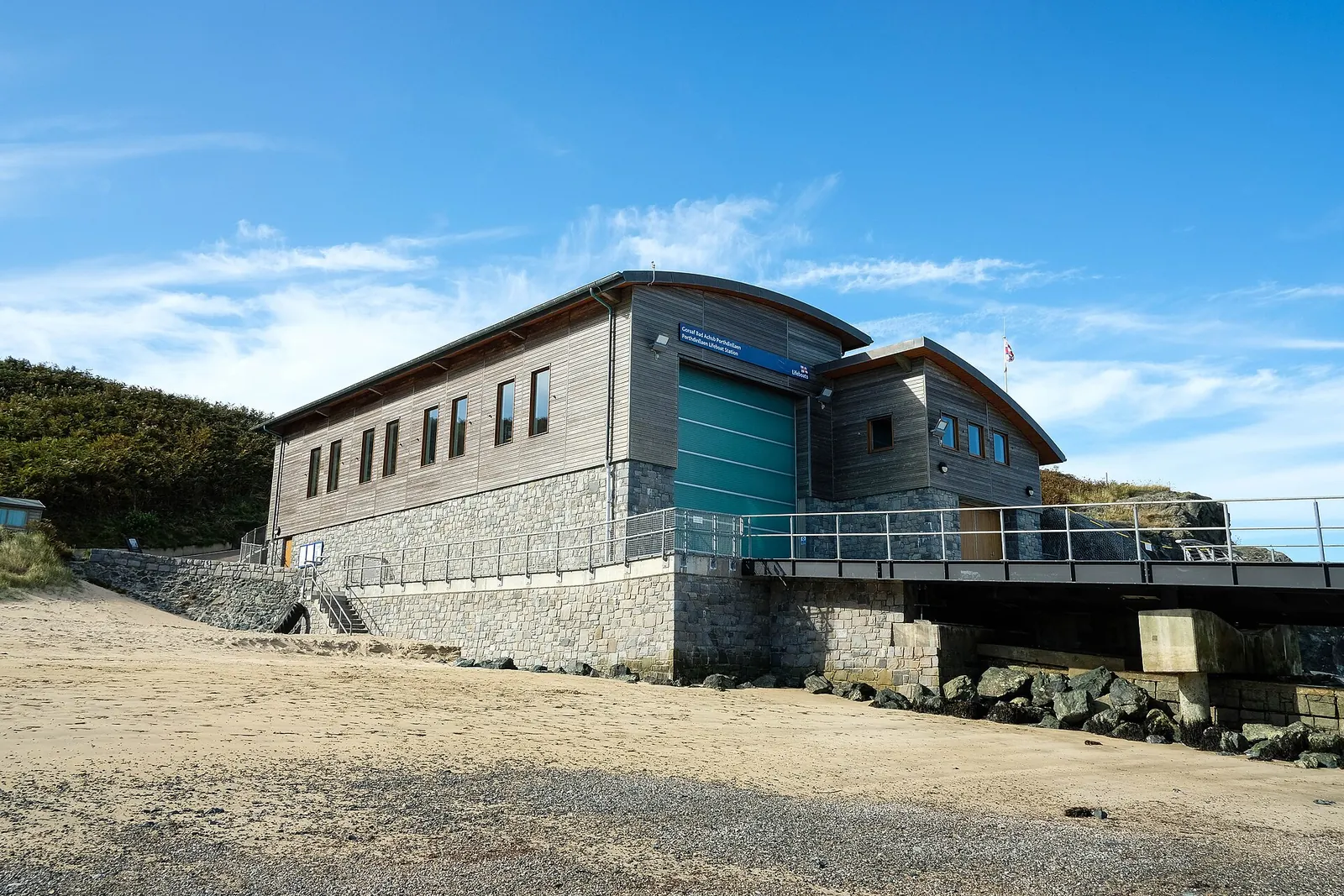 Porthdinllaen RNLI Lifeboat Station, a modern boathouse on the beach with a slipway to the sea.