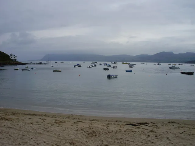 Small boats moored in the harbour at Porth Dinllaen, seen from the shore.