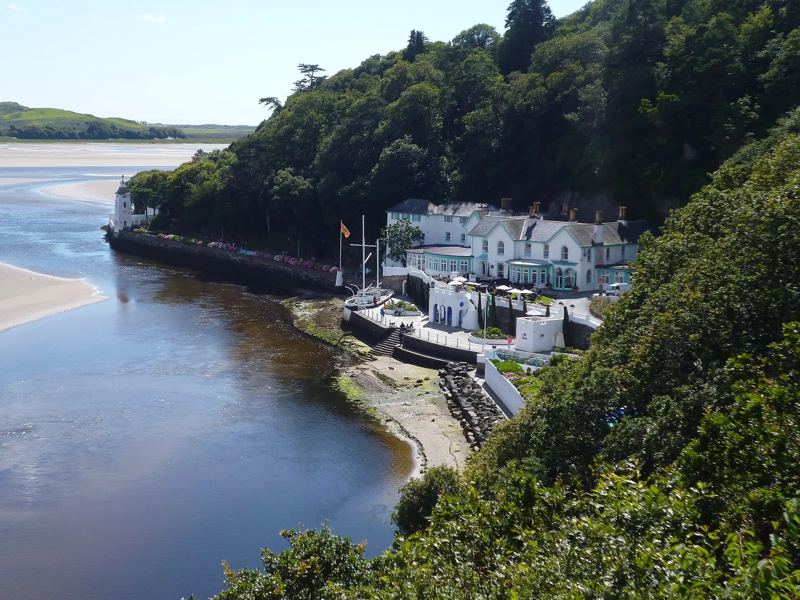 The Hotel Portmeirion on the water's edge, with a lighthouse folly and the Dwyryd estuary sands beyond.