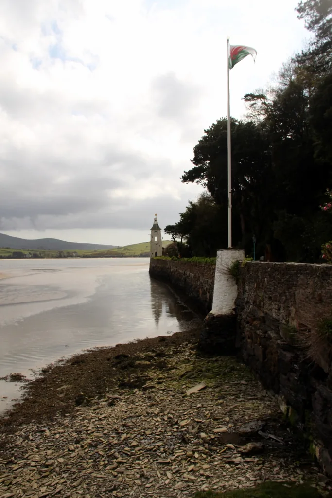 The estuary foreshore at Portmeirion, sand and water at the edge of the estate, a Welsh flag flying.