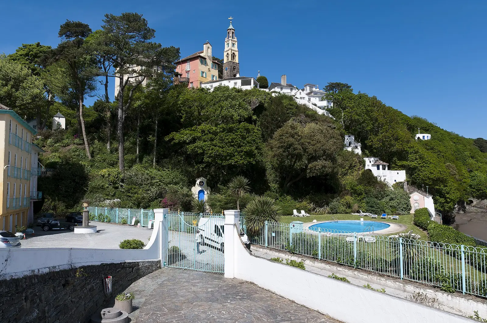 A wide elevated view combining the Hotel Portmeirion in the foreground with the built village rising above it.