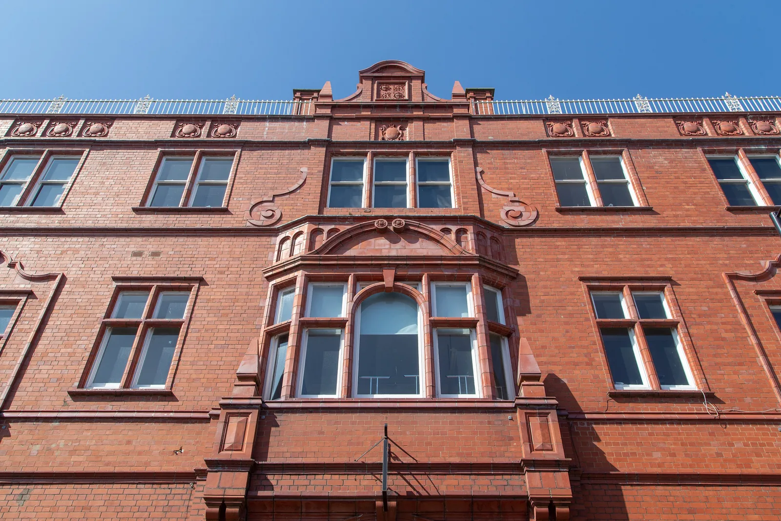 The red-brick frontage of Neuadd Dwyfor on Penlan Street, its moulded gable and bay window seen from below