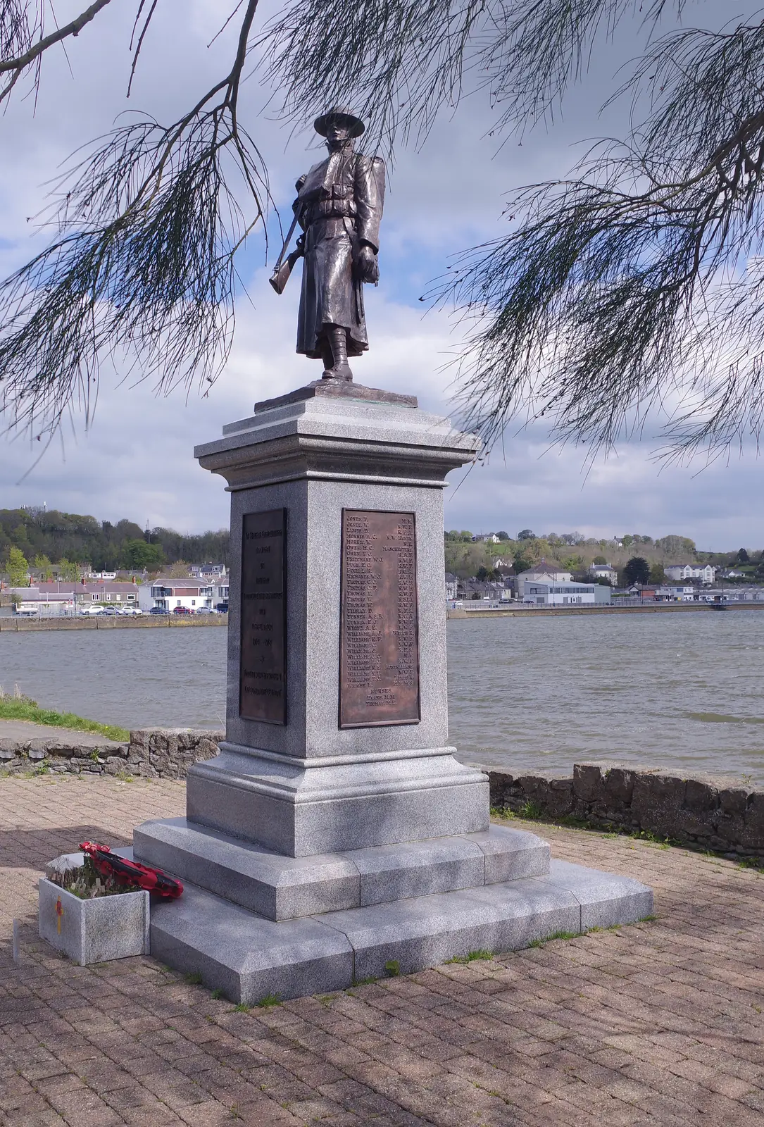 Pwllheli&rsquo;s war memorial, a bronze soldier on a granite plinth standing above the harbour