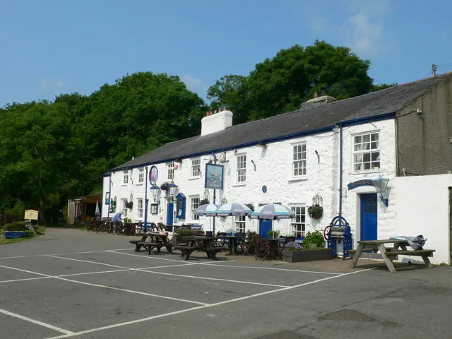 The Ship Inn, a white-painted pub with picnic tables and umbrellas, at the Red Wharf Bay seafront.