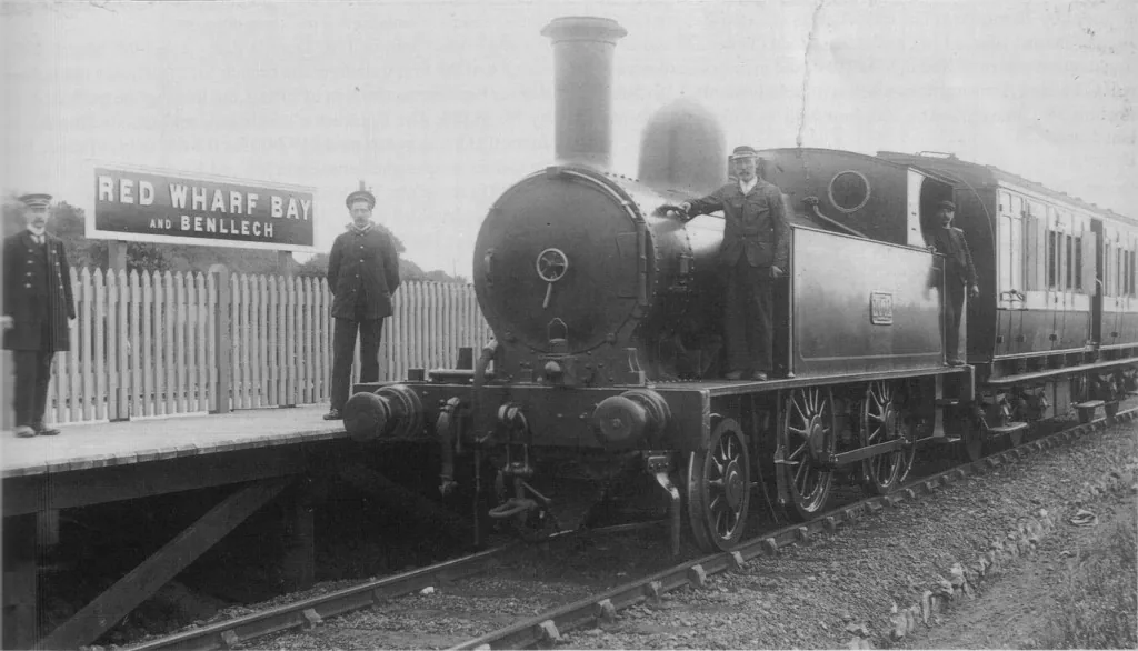 Archive photograph of Red Wharf Bay and Benllech railway station, 1909, showing a steam locomotive at the platform with the station name board visible.