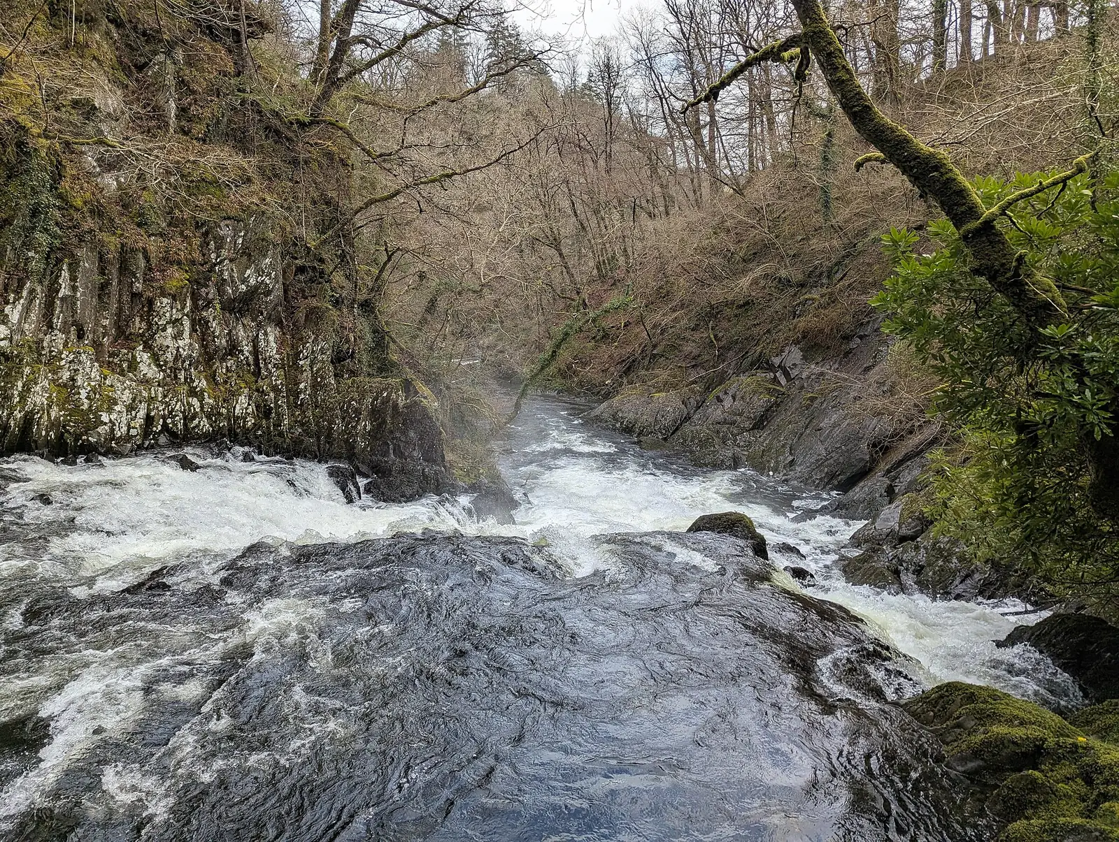 The Afon Llugwy gorge below Swallow Falls, mist rising off the water between rocky, wooded banks.