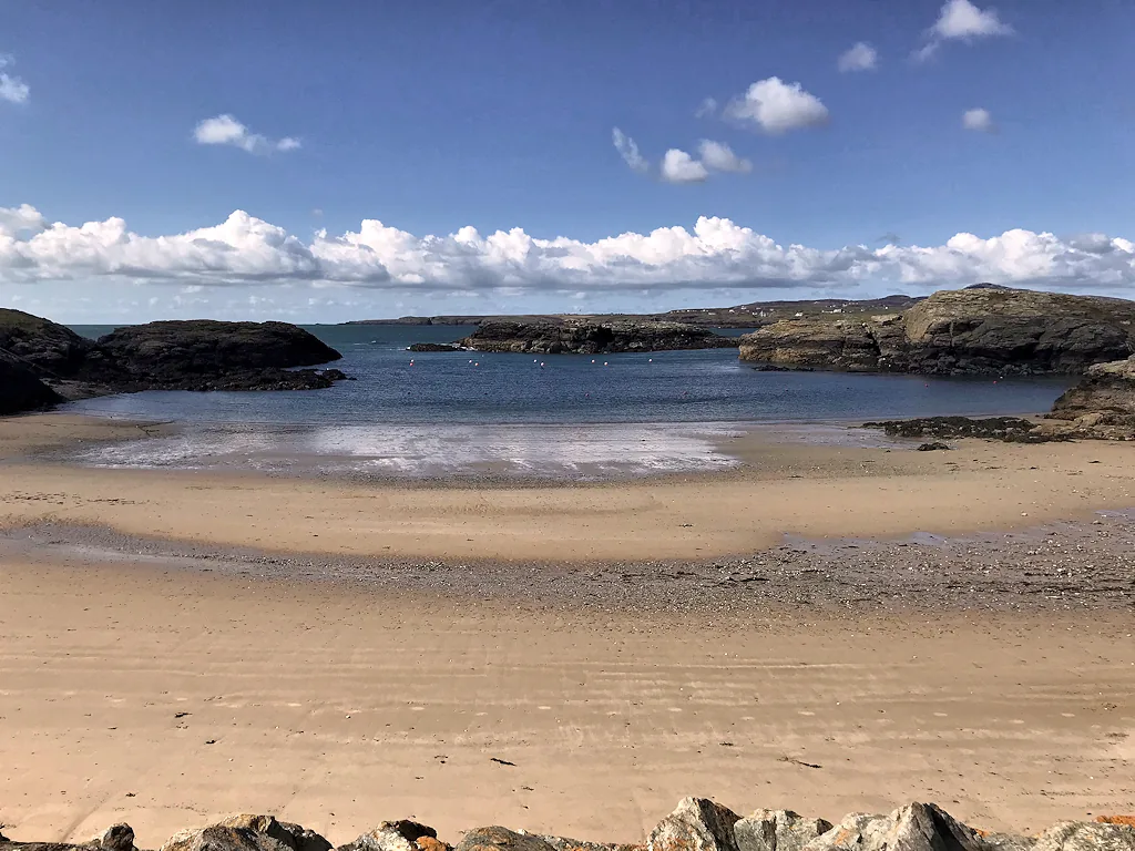 Porth Diana, a rocky cove with calm water and swim buoys, reached via Ravenspoint Road.