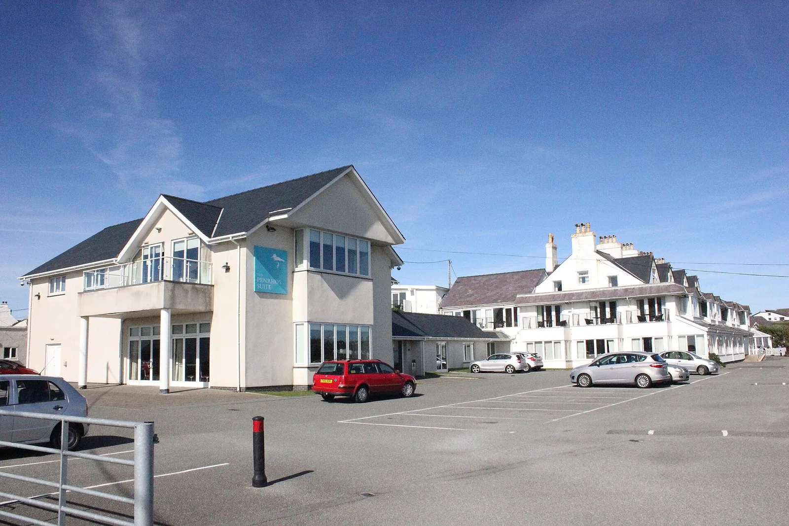 The Trearddur Bay Hotel's white frontage and car park, overlooking the bay.