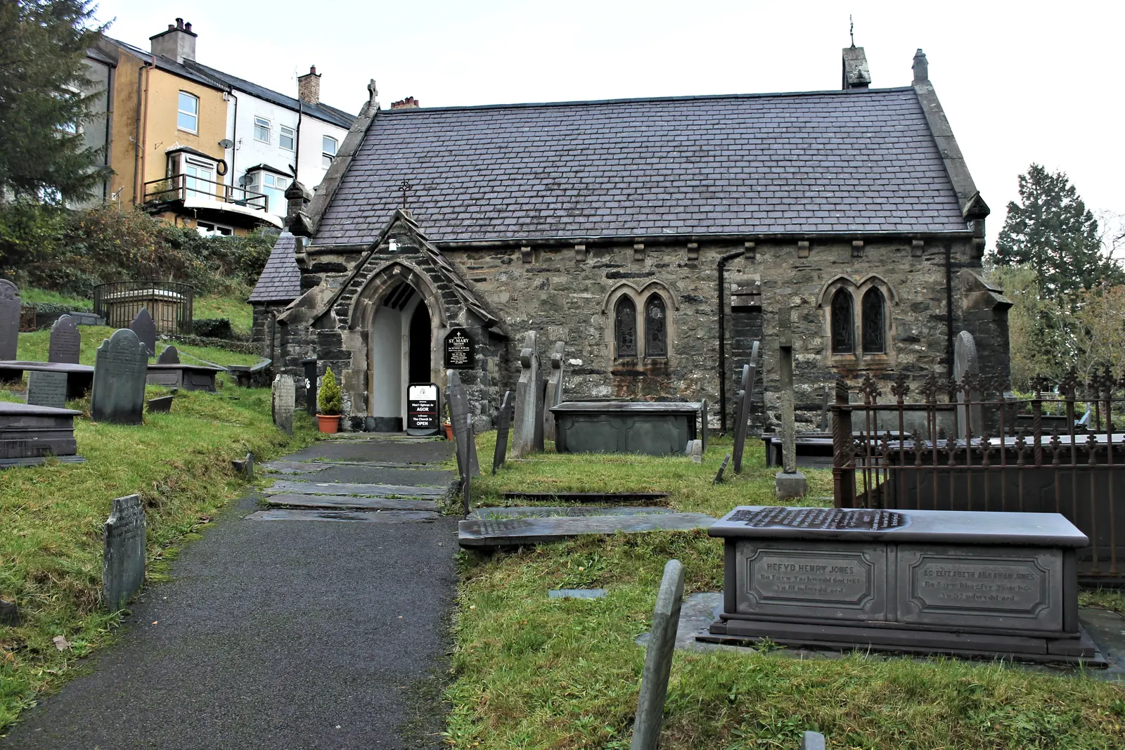 St Mary's Church, Trefriw, its porch and slate roof above a churchyard of chest tombs, houses rising behind