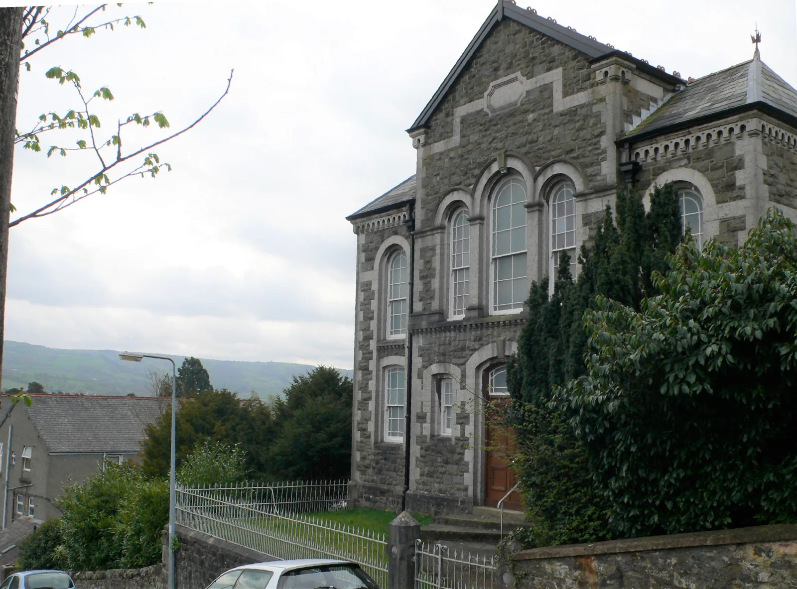 Capel Ebenezer at Trefriw, a tall stone chapel with round-arched windows standing above the road