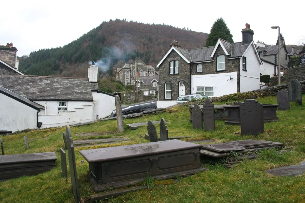 Trefriw seen over the tombs in St Mary's churchyard, slate roofs below a steep wooded hill