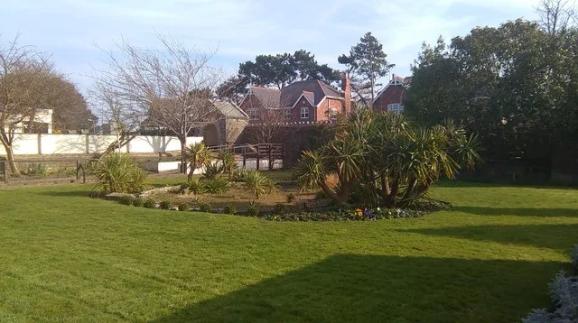A garden lawn at the Welsh Mountain Zoo, with estate buildings and trees beyond.
