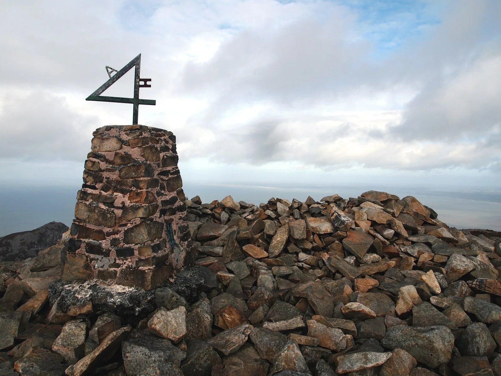 The trig pillar on Garn Ganol under heavy cloud, with the sea just visible beyond