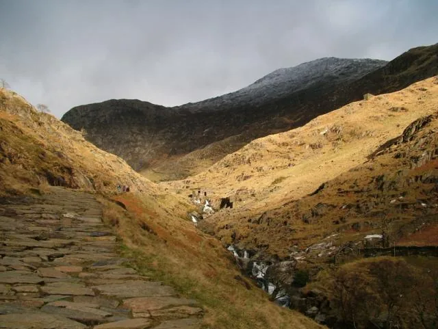The paved Watkin Path climbing a valley toward a snow-dusted summit